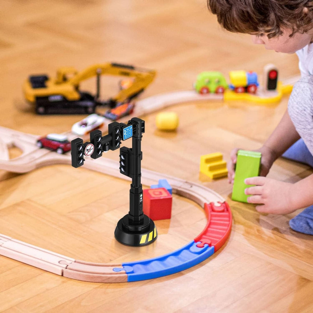 Black traffic light model standing on play track with toy vehicles around it