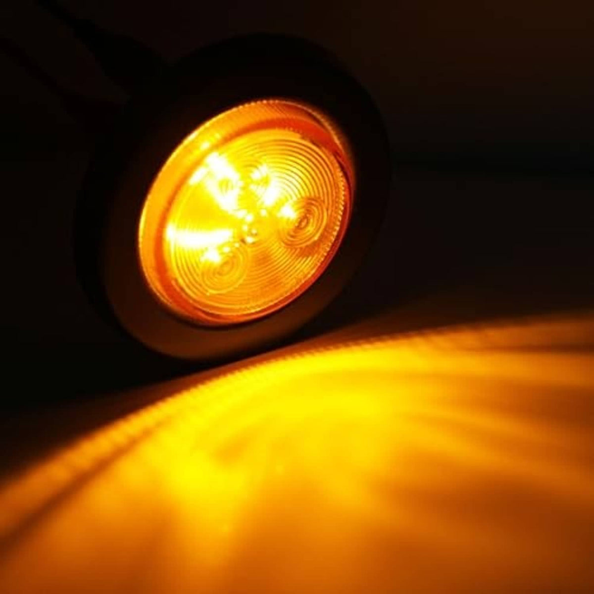 Single amber round LED trailer side marker light lit inside black housing