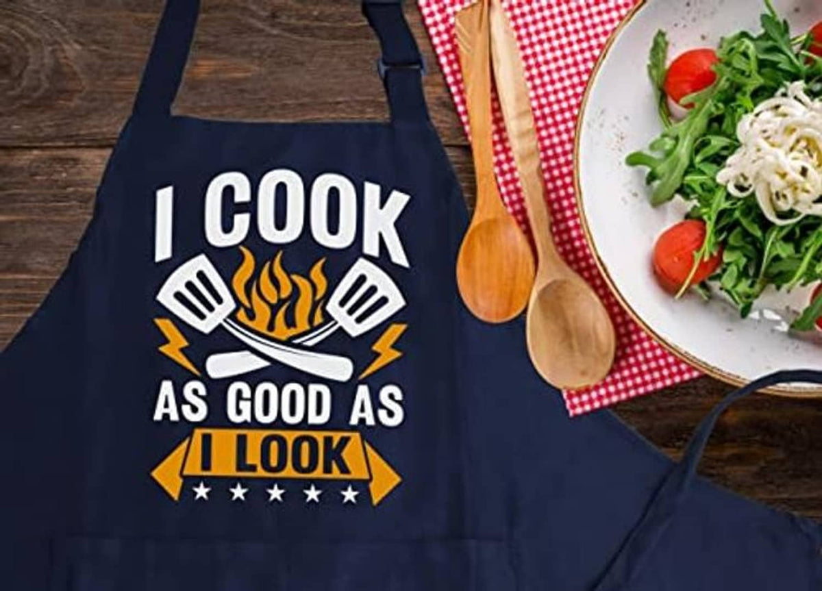 Navy cooking apron with “I COOK AS GOOD AS I LOOK” graphic and crossed utensils design