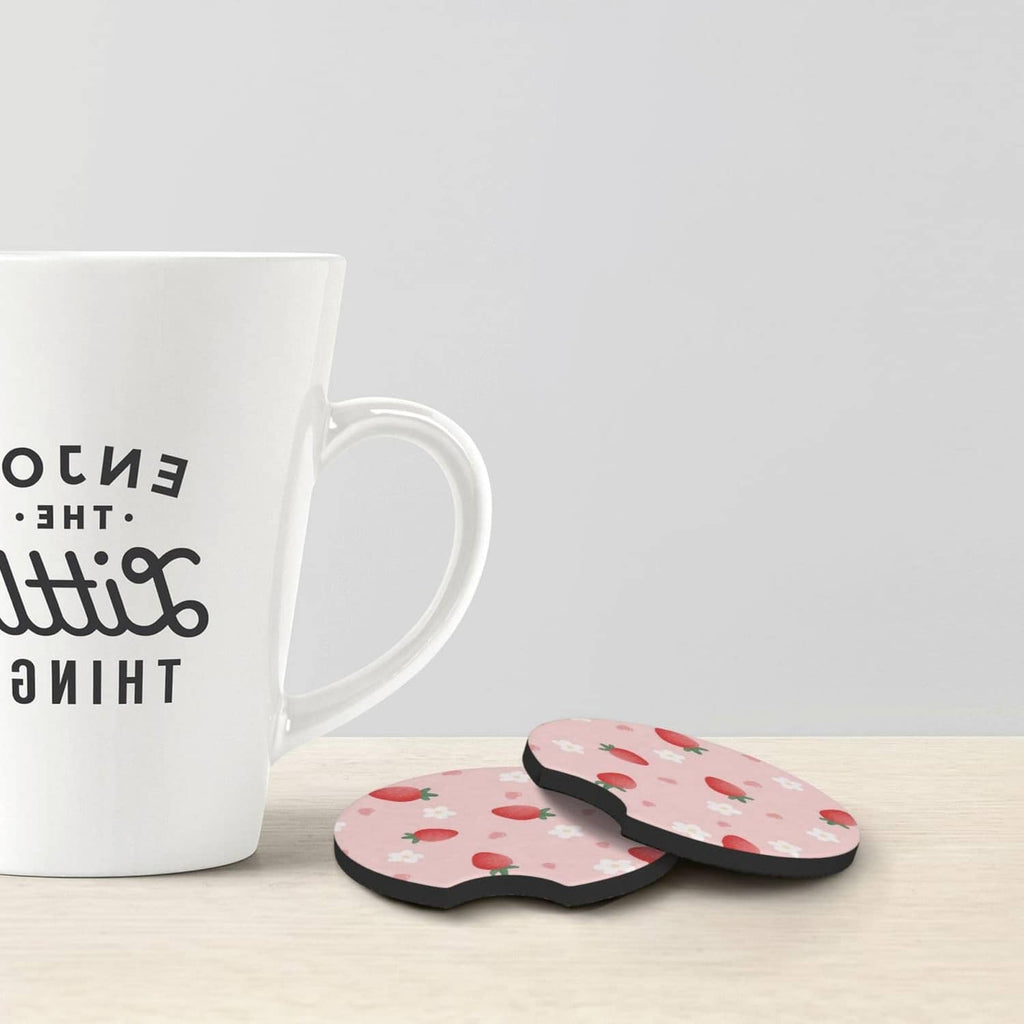 Pink strawberry-pattern car cup coaster set on table beside a mug