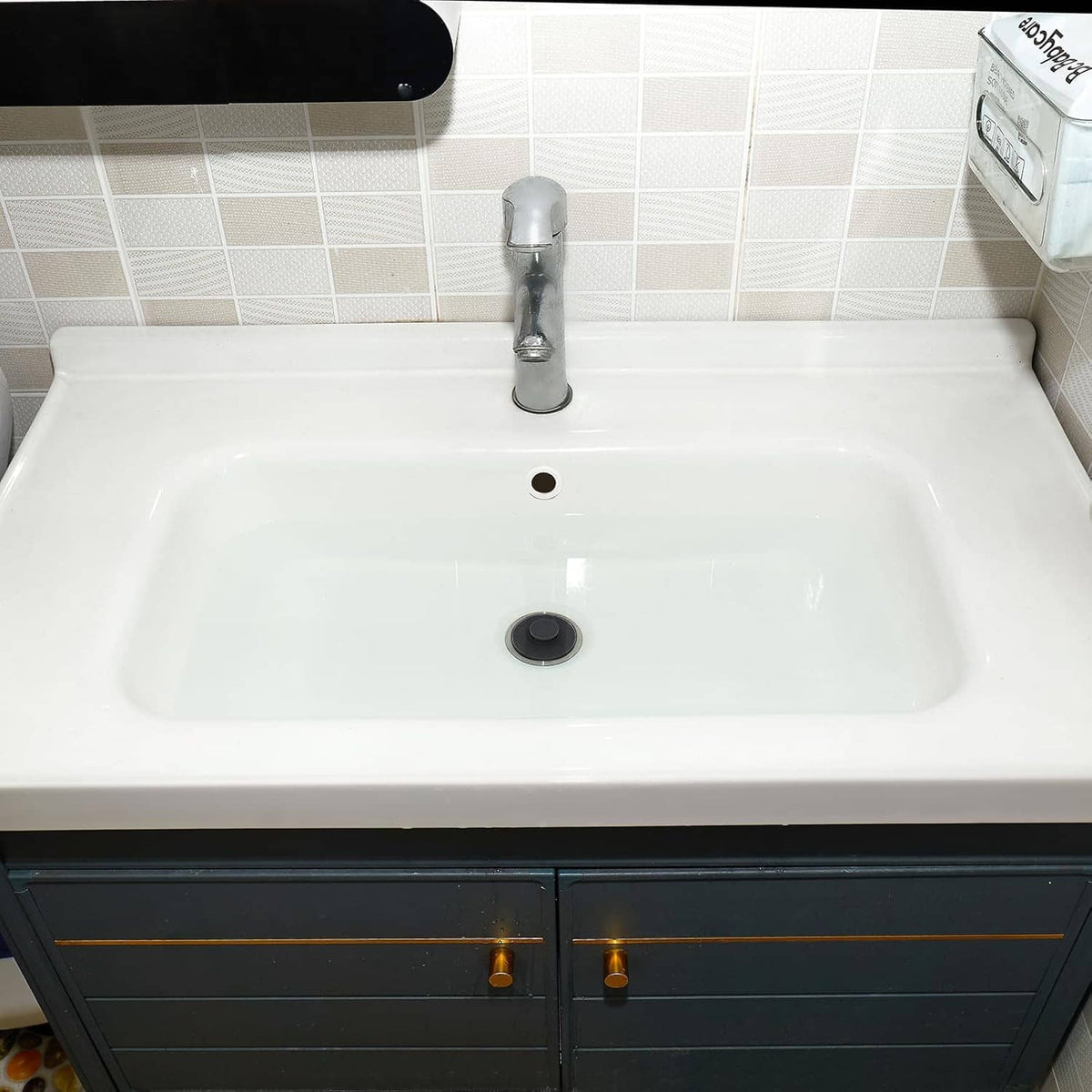 White bathroom sink with installed dark gray round drain stopper plug