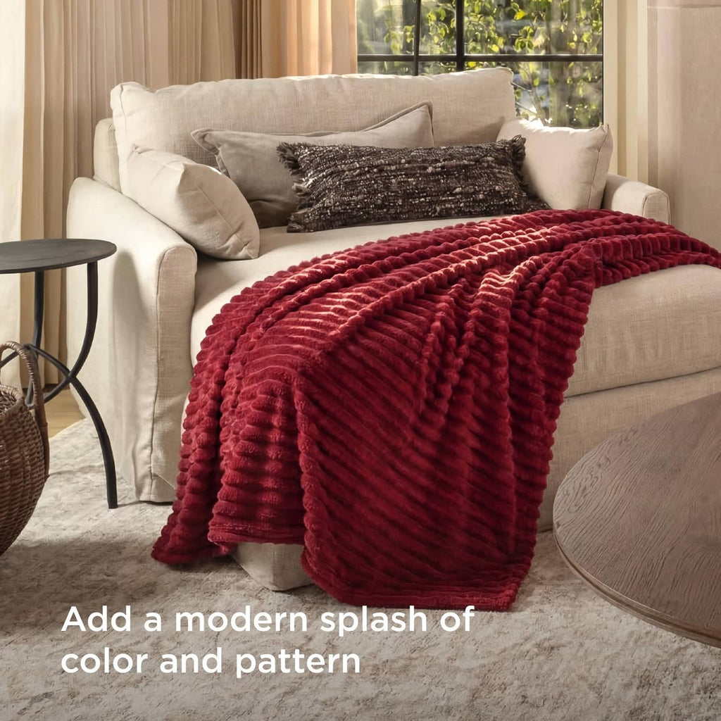 Red plush ridged throw blanket draped over sofa arm on living room couch