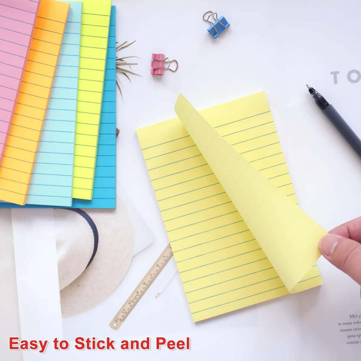 4x6 lined sticky note being peeled and stuck, with assorted colors on paper