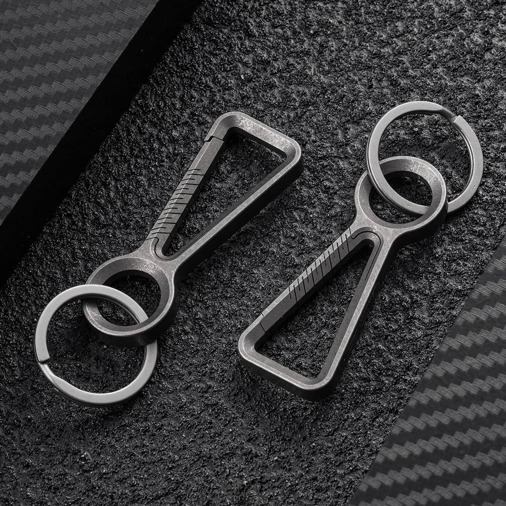 Titanium keychain clip carabiners with key rings on textured dark surface