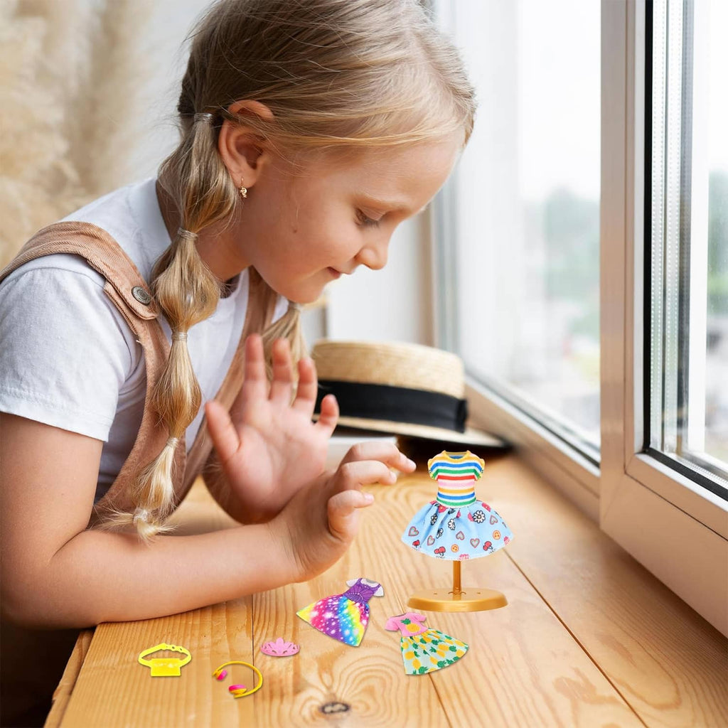 Girl doll outfit pieces on a wooden table, with small dress and top styles