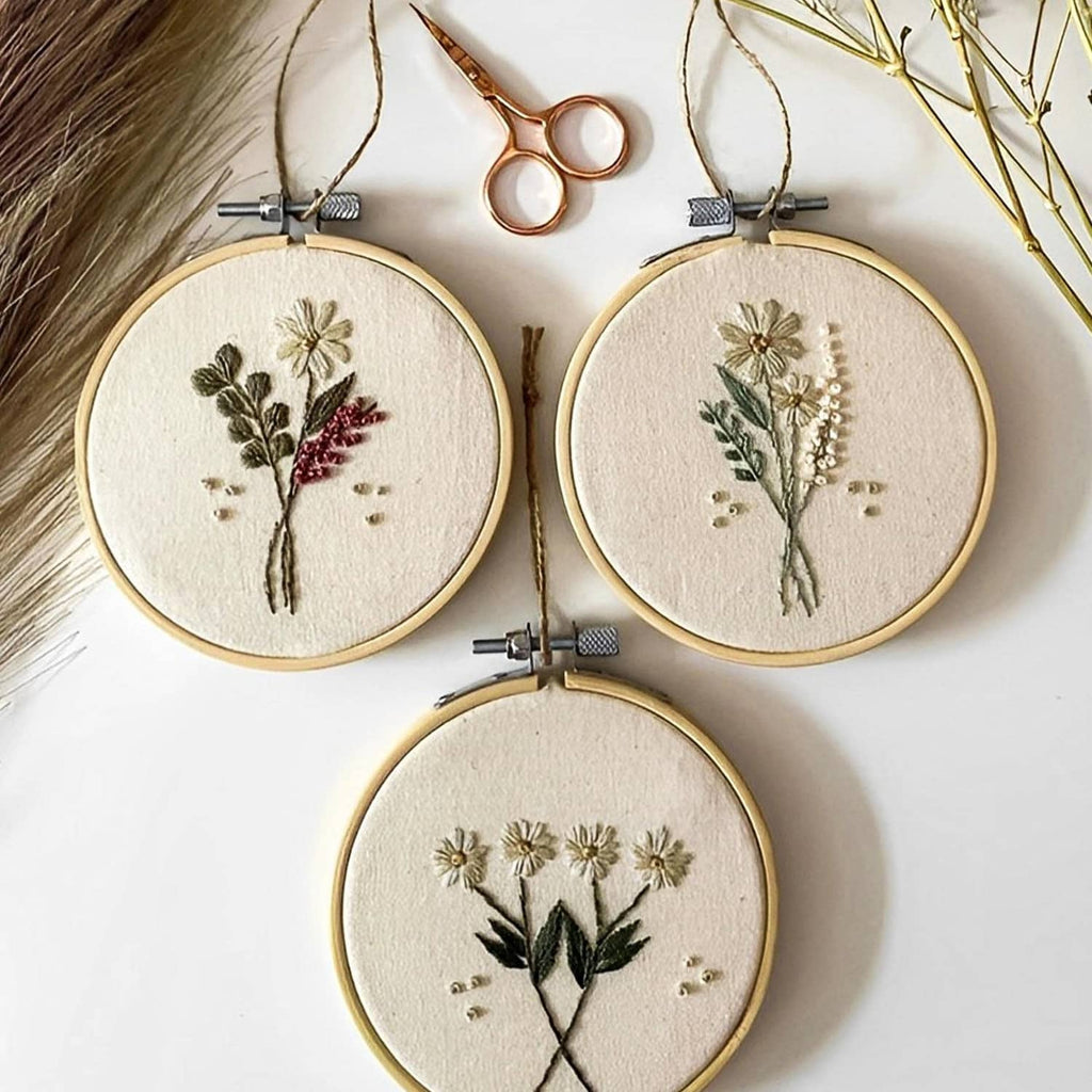 Three nature bamboo embroidery hoops with floral embroidery and metal screw clamps