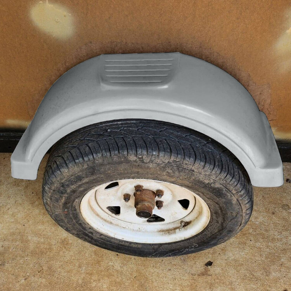 Gray plastic wheel fender mounted over trailer wheel, vented top section