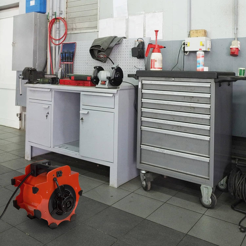 Orange portable blower fan dryer on workshop floor next to tools and cabinets