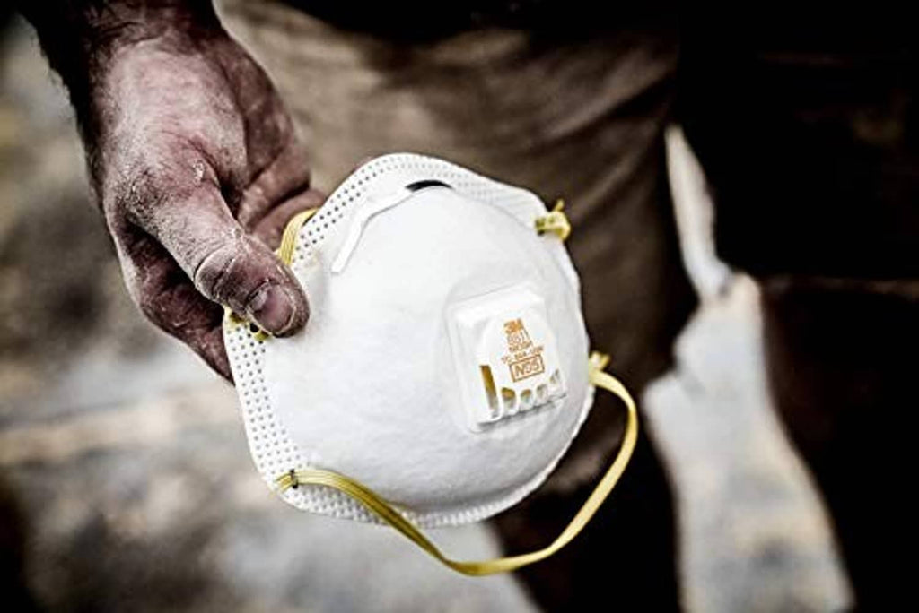 White 3M N95 respirator with Cool Flow valve, held by gloved hand