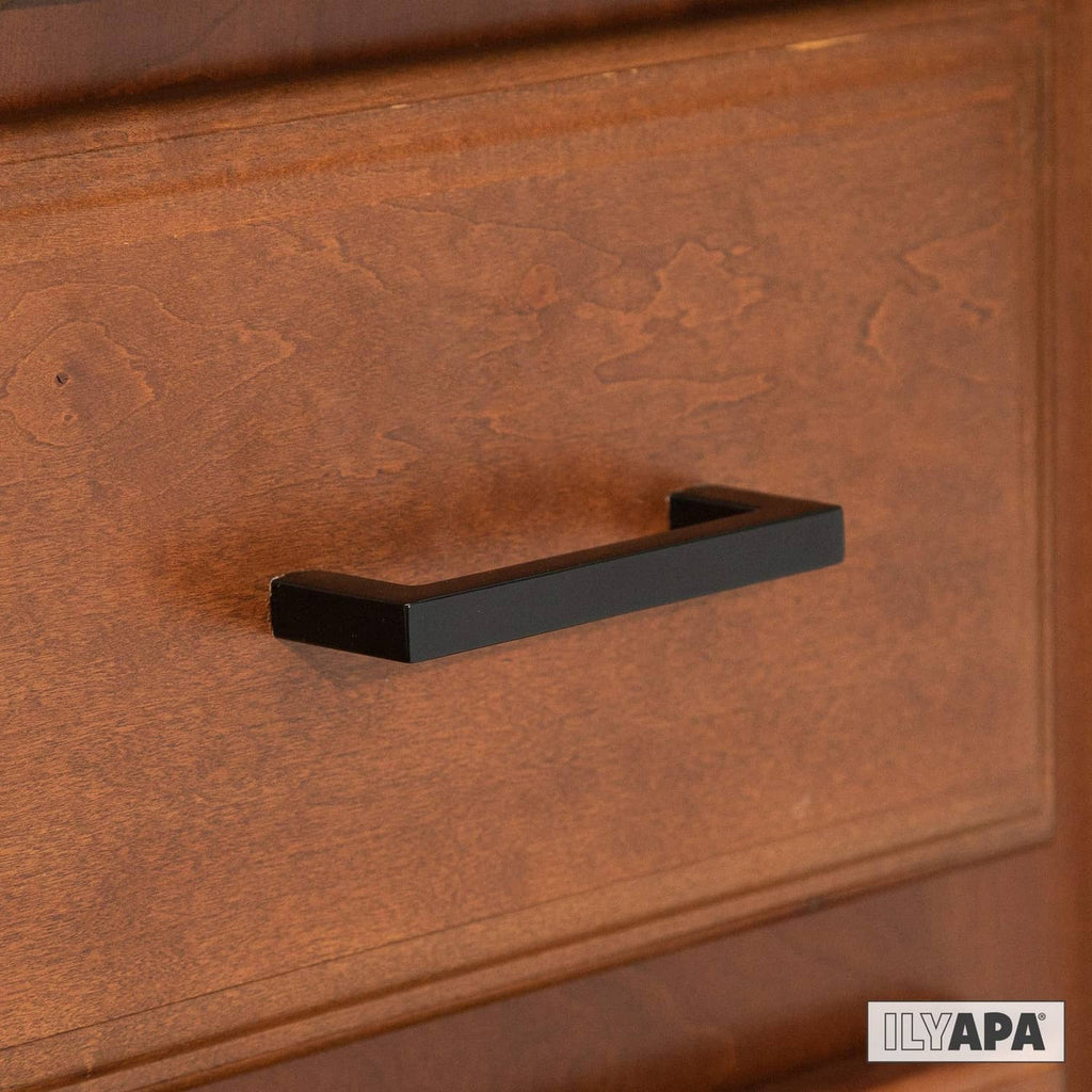 Matte black square cabinet pull on wooden cabinet door, centered