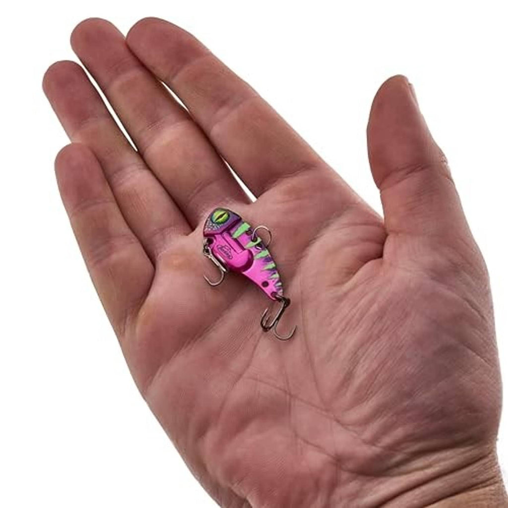 Blade bait fishing lure on open palm, small magenta-red body with green-black eye
