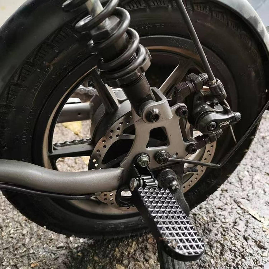 Mounted black textured footpeg on scooter near front brake and wheel