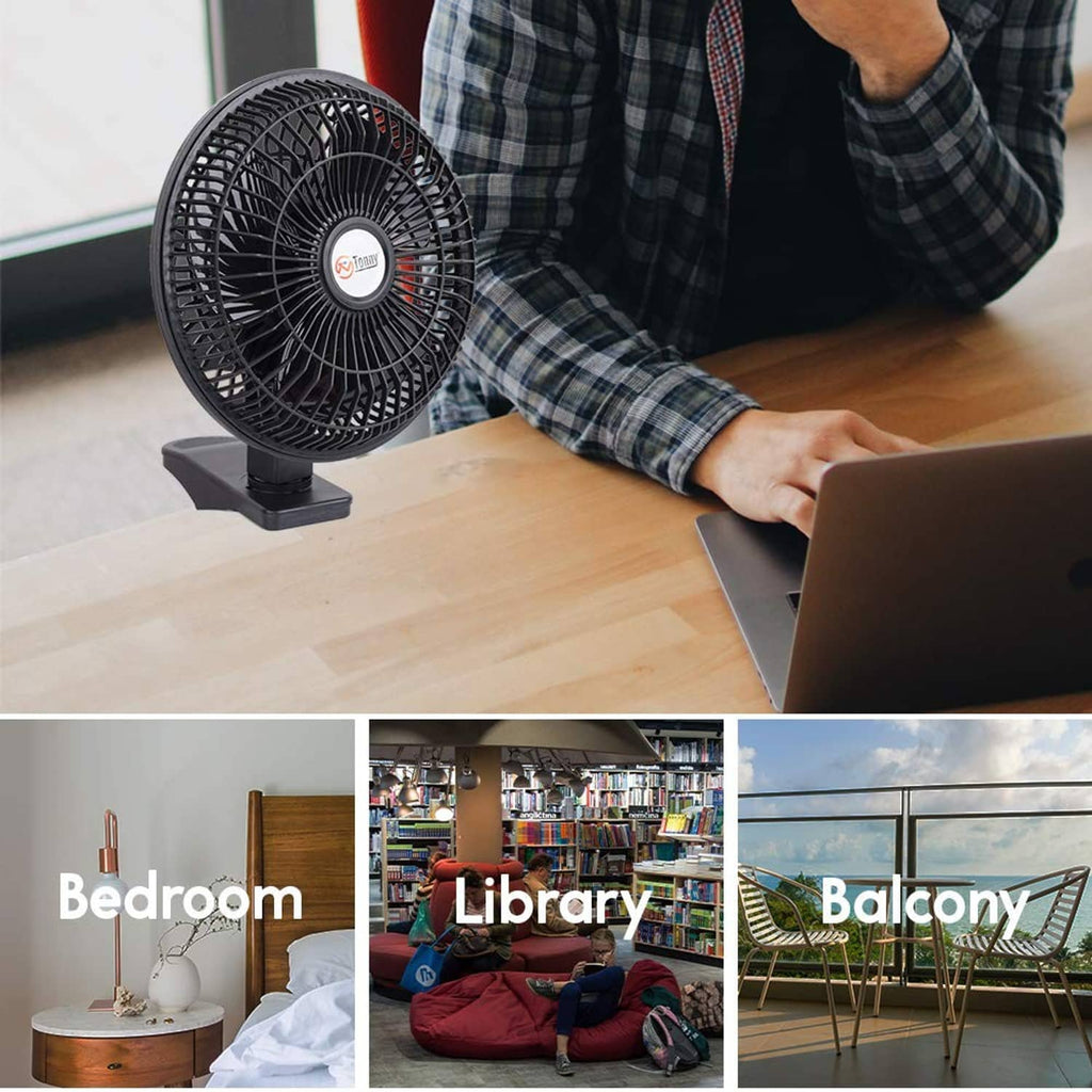 Black clip-on desk fan on tabletop aimed toward a laptop for home office cooling.