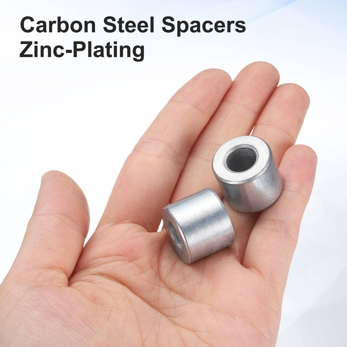 Galvanized steel spacer bushing, silver, small cylindrical pieces in hand
