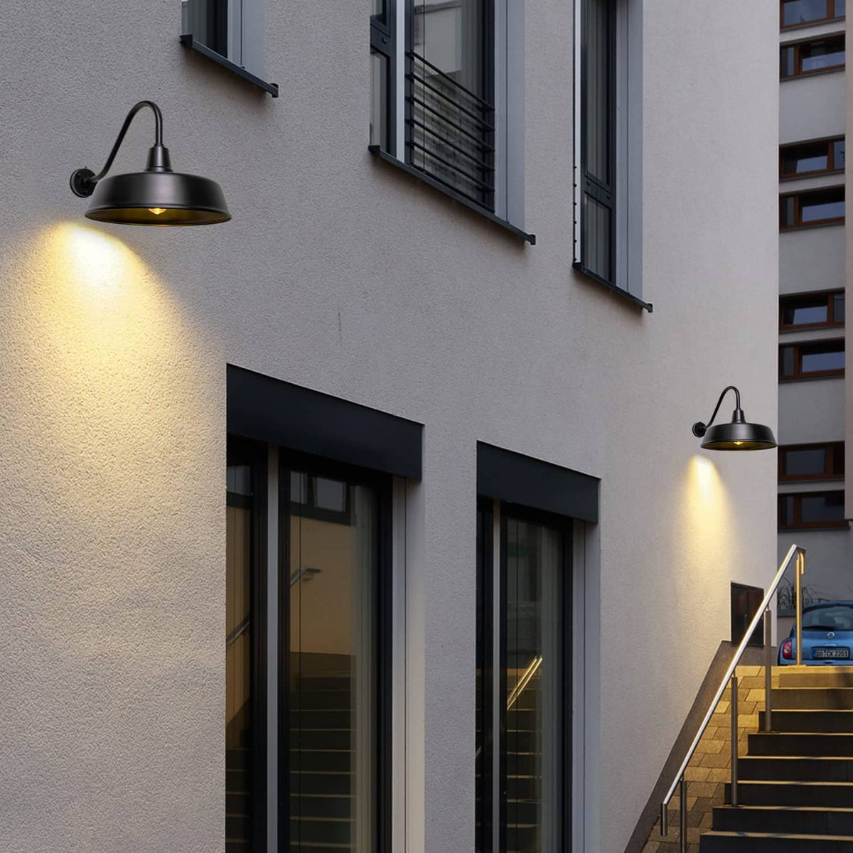 Black gooseneck barn lights mounted on building exterior walls with warm glow