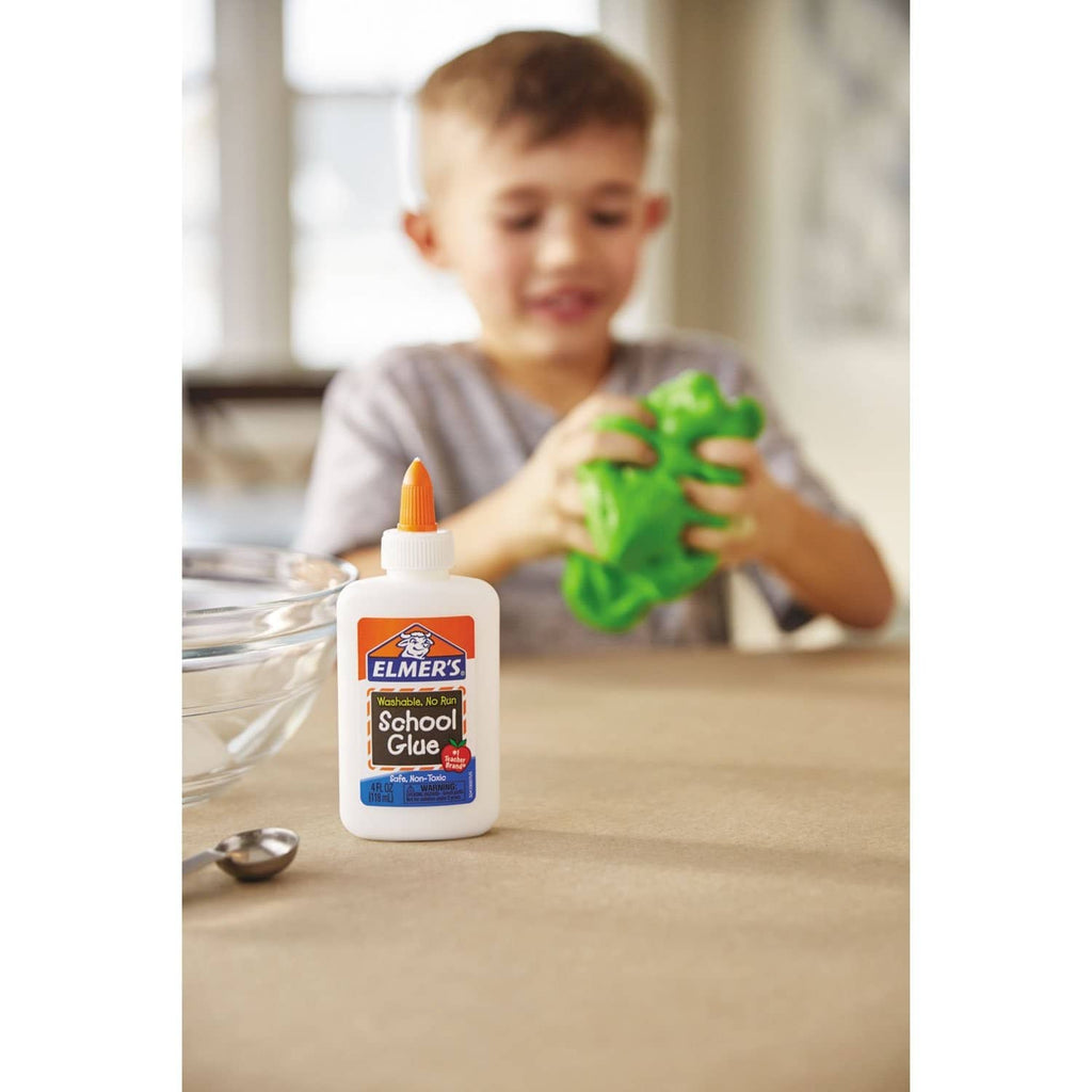 Child playing with bright green slime next to a bottle of Elmer’s school glue