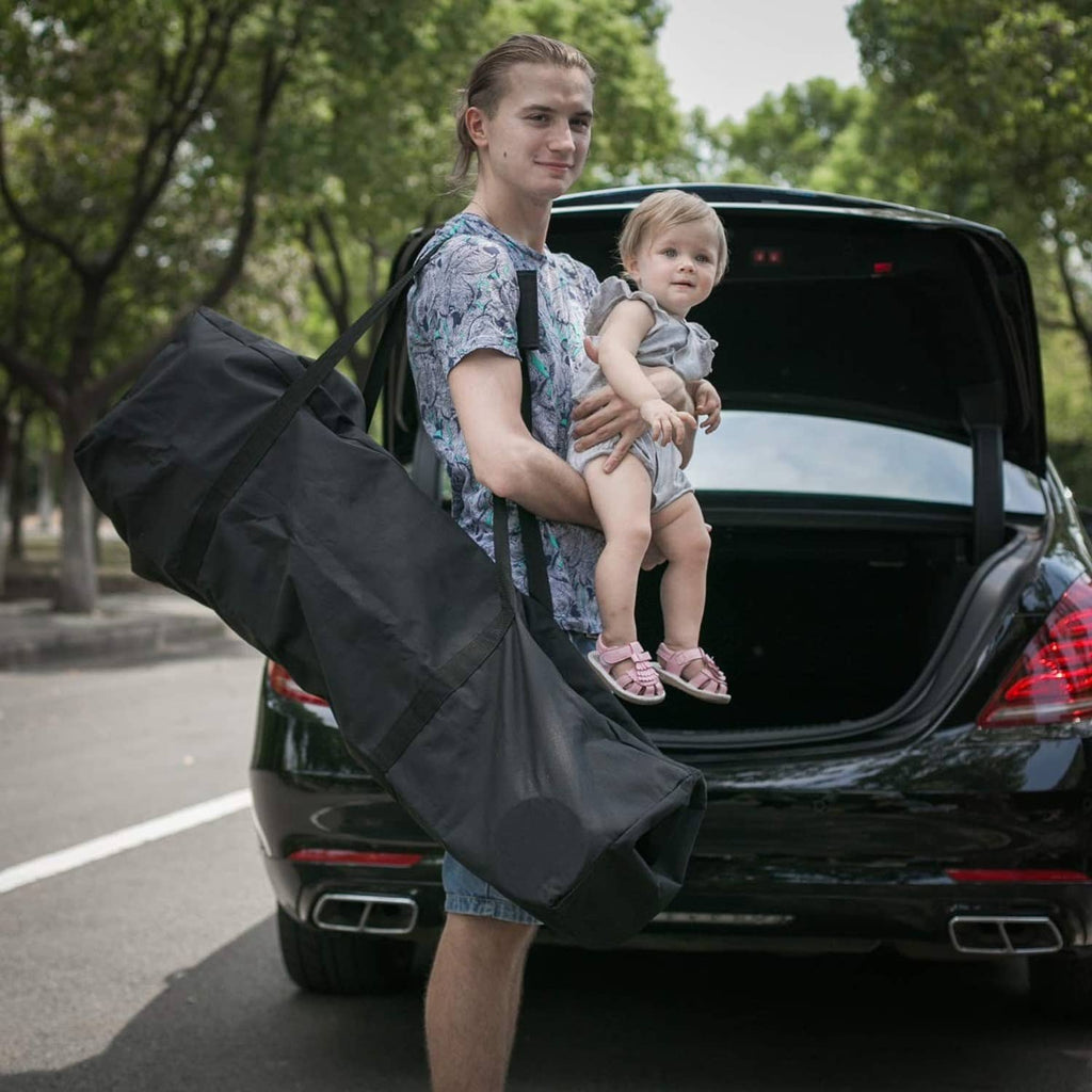 Black long duffel bag carried with top handles in front of an open car trunk