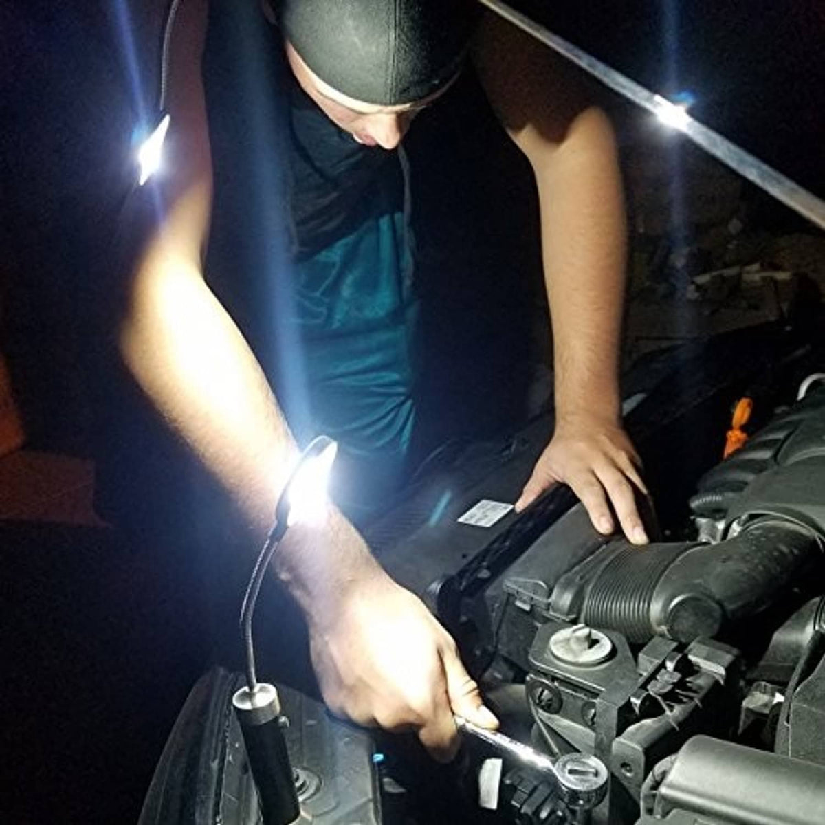 Magnetic LED COB light set shining in car engine bay while a person holds one light