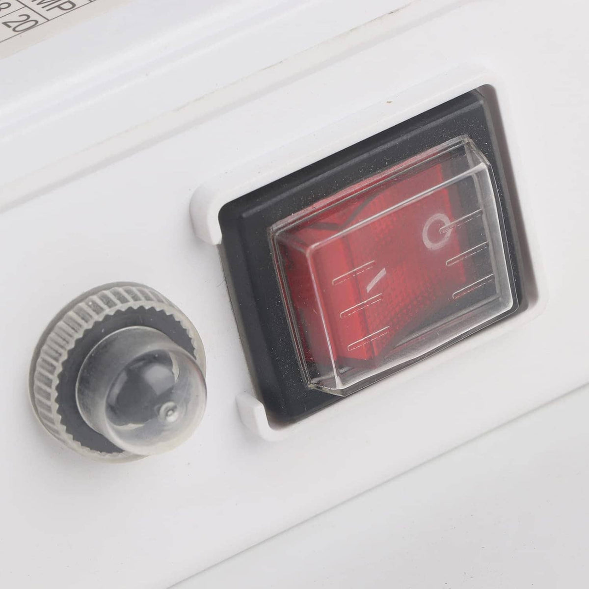 Close-up of white submersible pump controller control window with red indicator and knob.