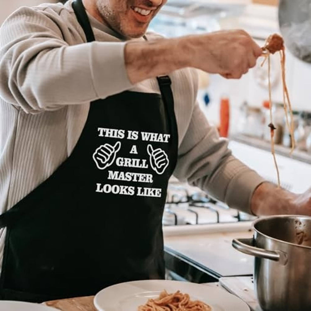 Black grilling apron with “Grill Master looks like” white graphic, front pocket