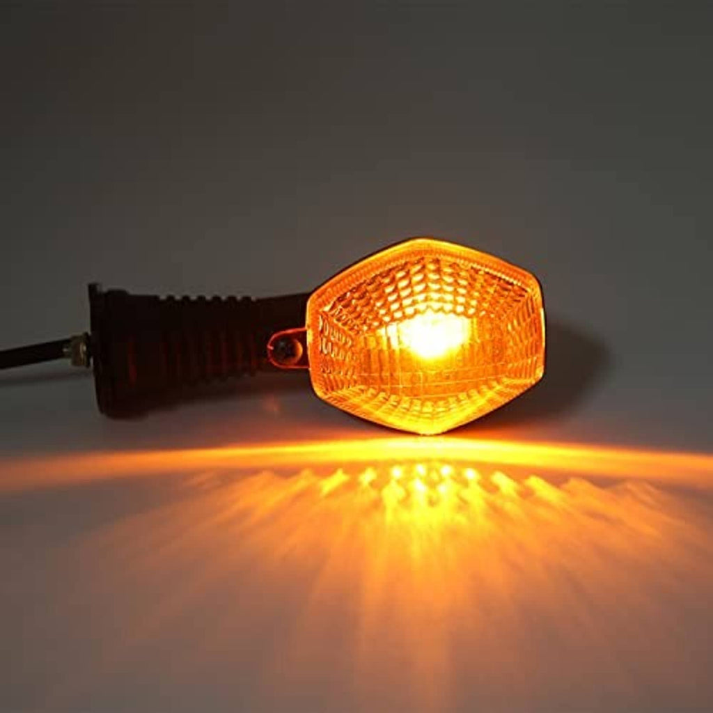 Lit amber motorcycle turn signal lamp with black housing and warm glow lens