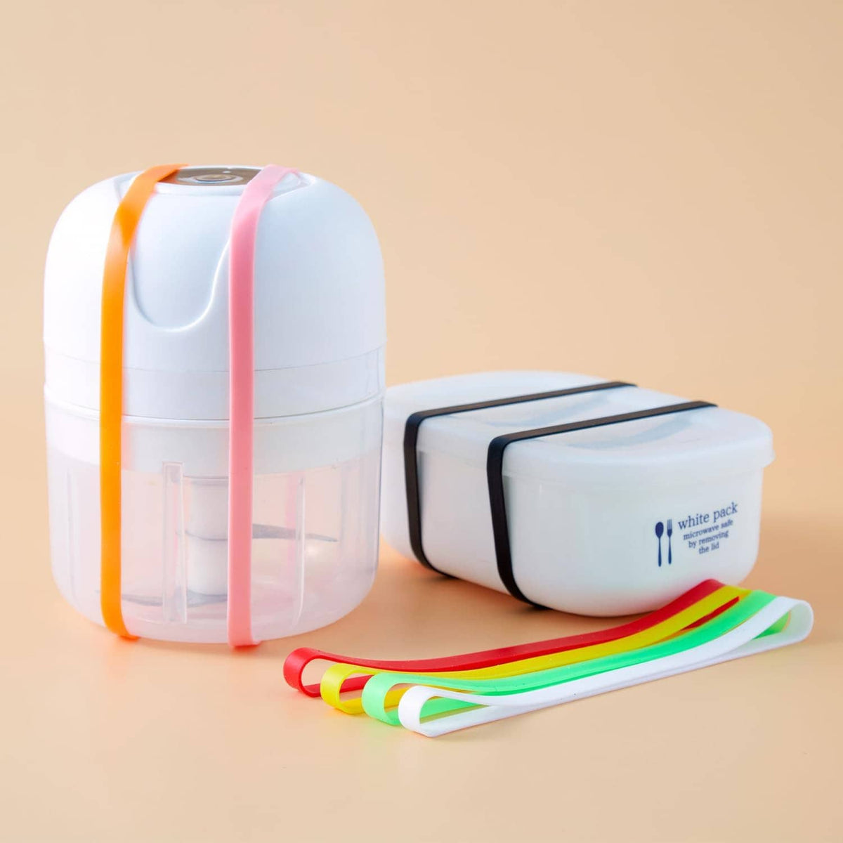 Rainbow silicone elastic bands rolled alongside white storage cases, curved loops