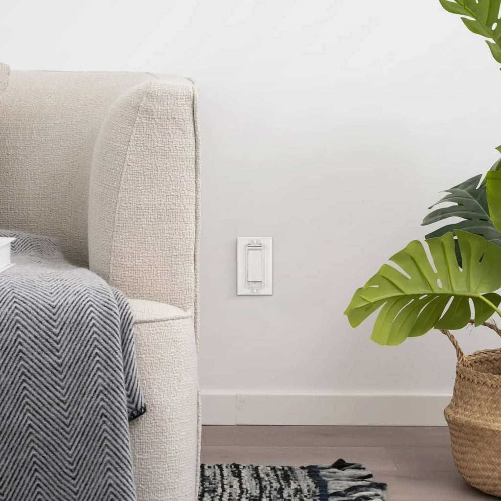 Clear childproof light switch guard on the wall next to a living room sofa.
