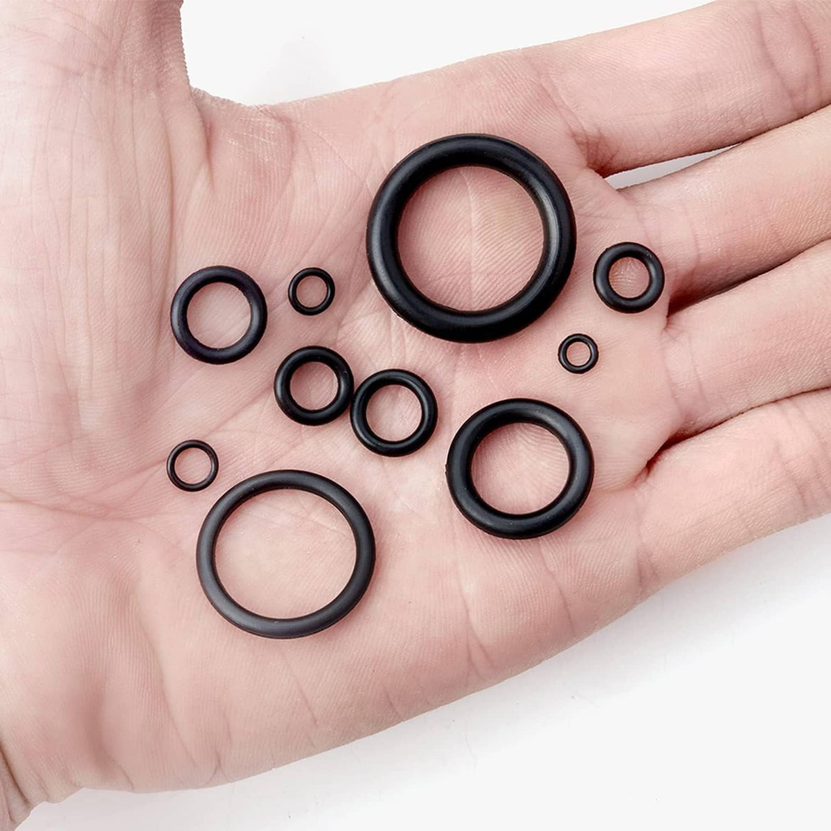 Hand holding black NBR O-rings of assorted sizes on palm