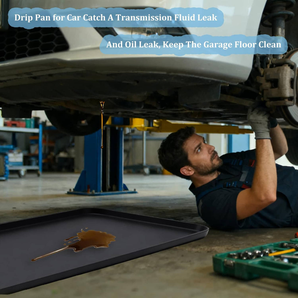 Black under-car drip pan catching brown fluid leak in auto repair bay