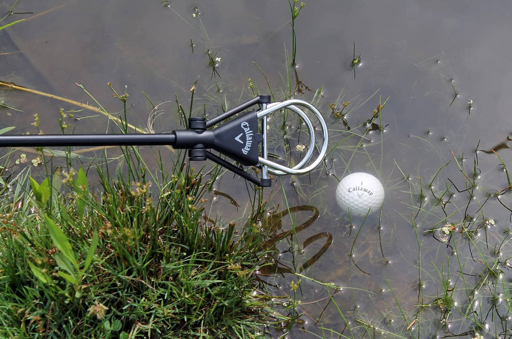 Telescopic ball retriever in water with white golf ball near the scoop