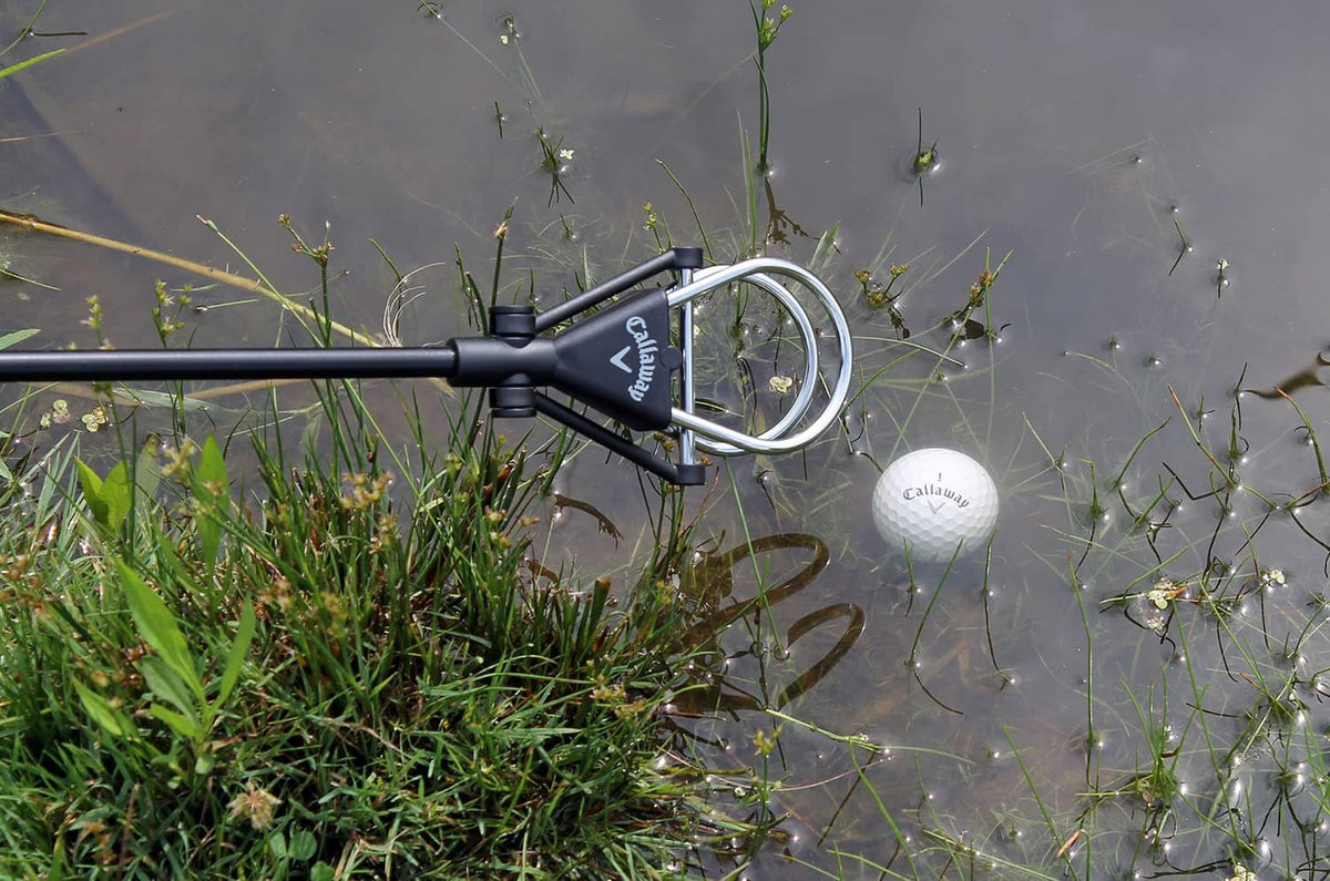 Telescopic ball retriever in water with white golf ball near the scoop