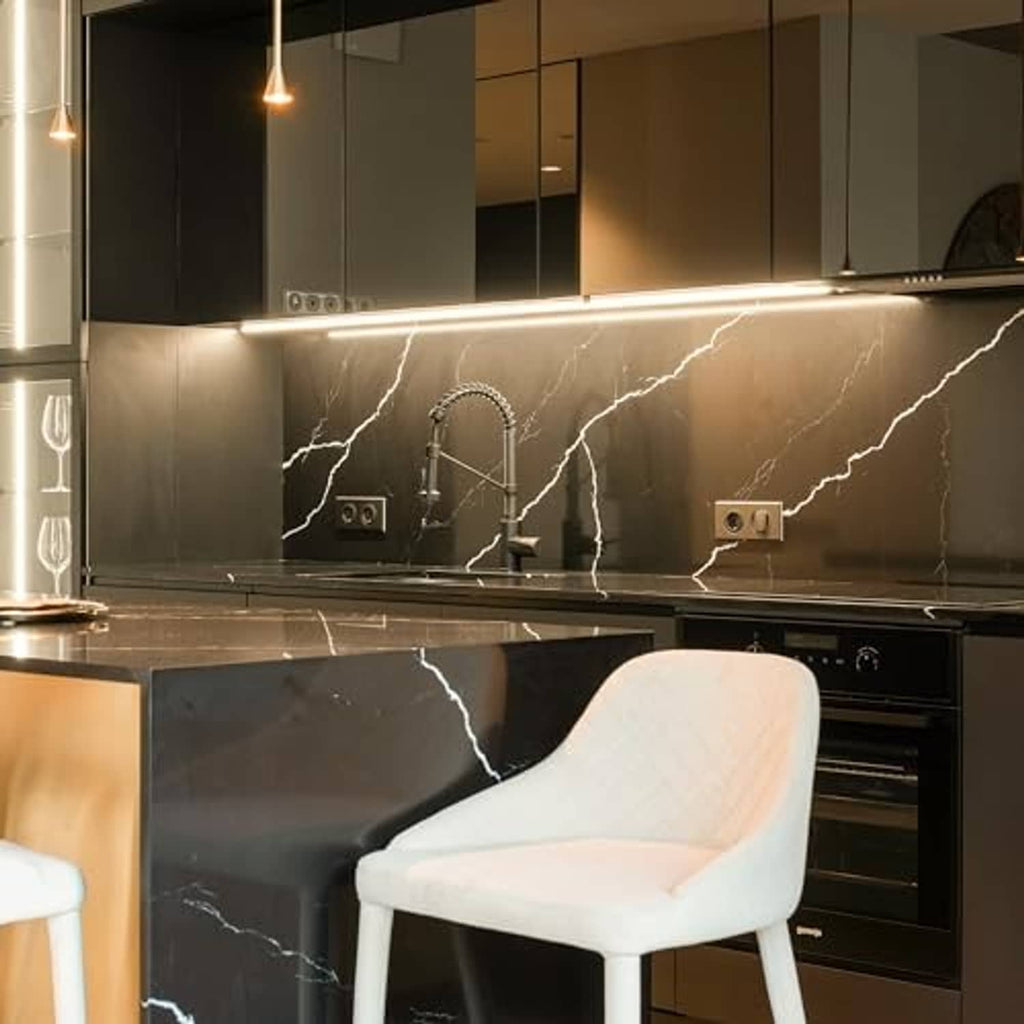 Warm white kitchen under-cabinet lighting with T5 LED tube-style bulbs on dark backsplash