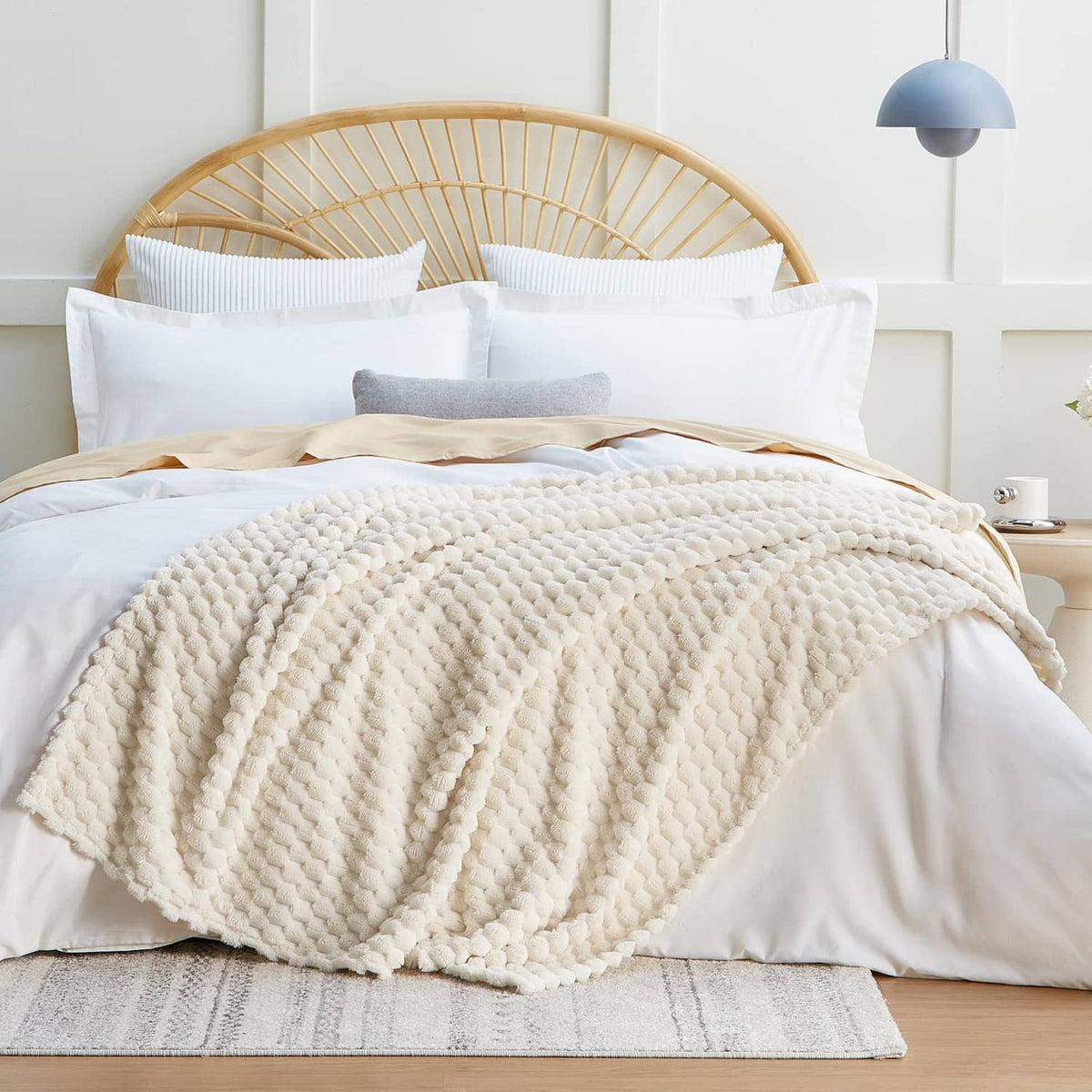 Cream textured fleece throw blanket with curved 3D ridges, draped on bed