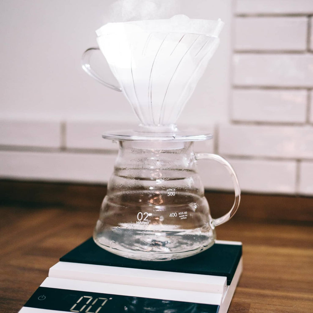 White V60 paper coffee filter on a glass carafe with brewed coffee
