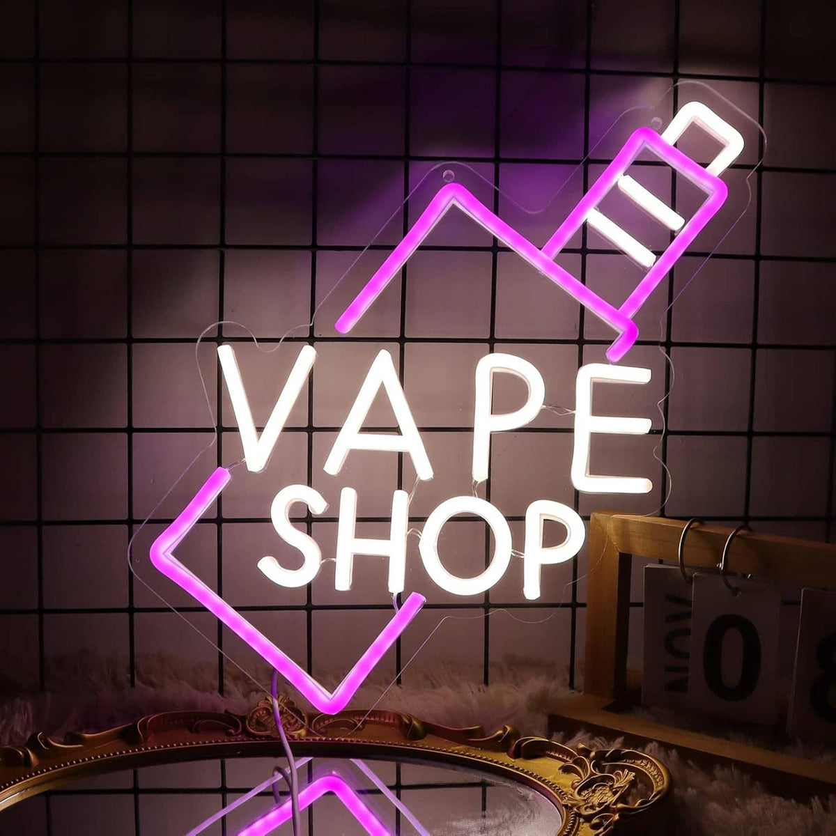 VAPE SHOP neon sign with pink arrow outline and white letters on a gold decorative stand