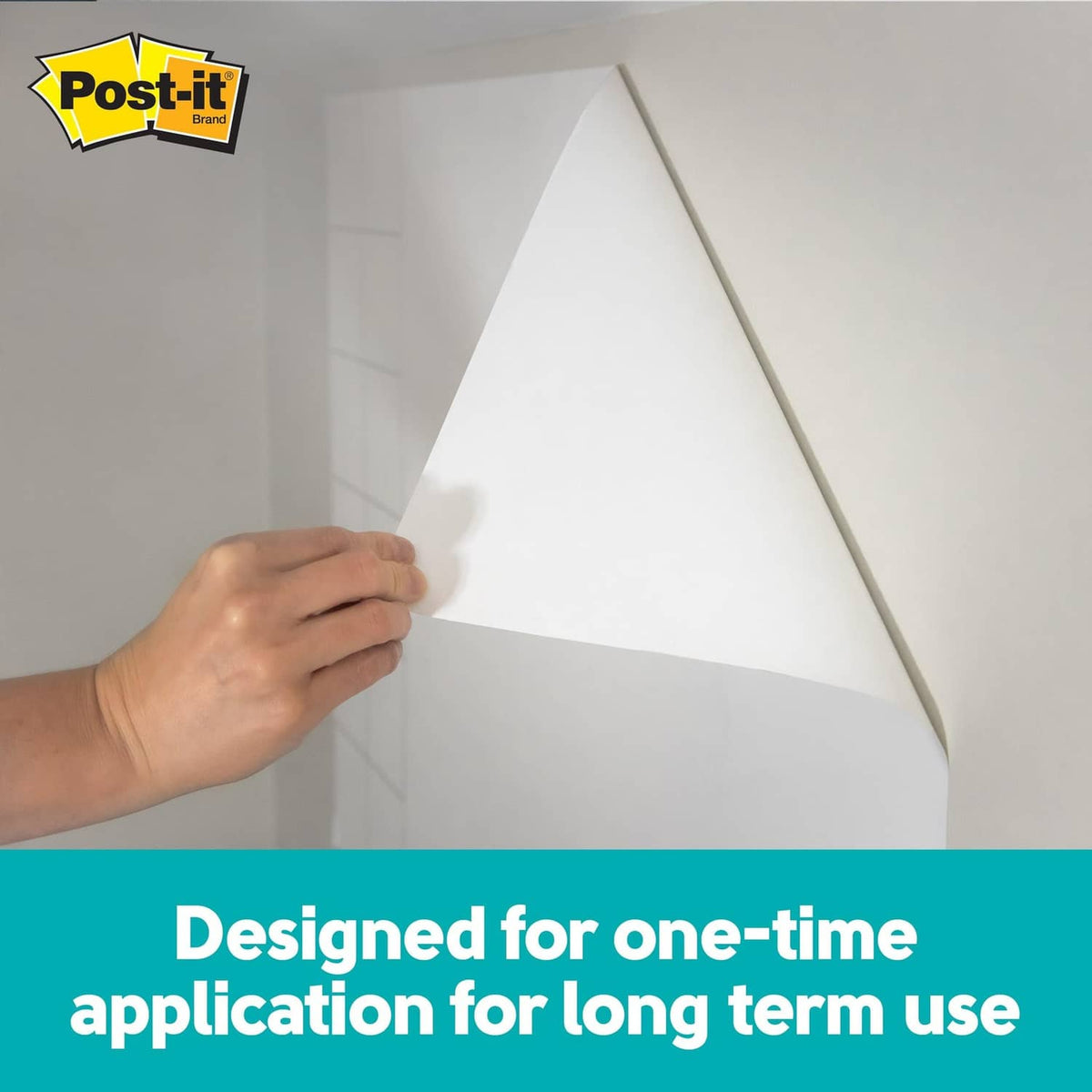 Person peeling a white write surface sheet from a wall
