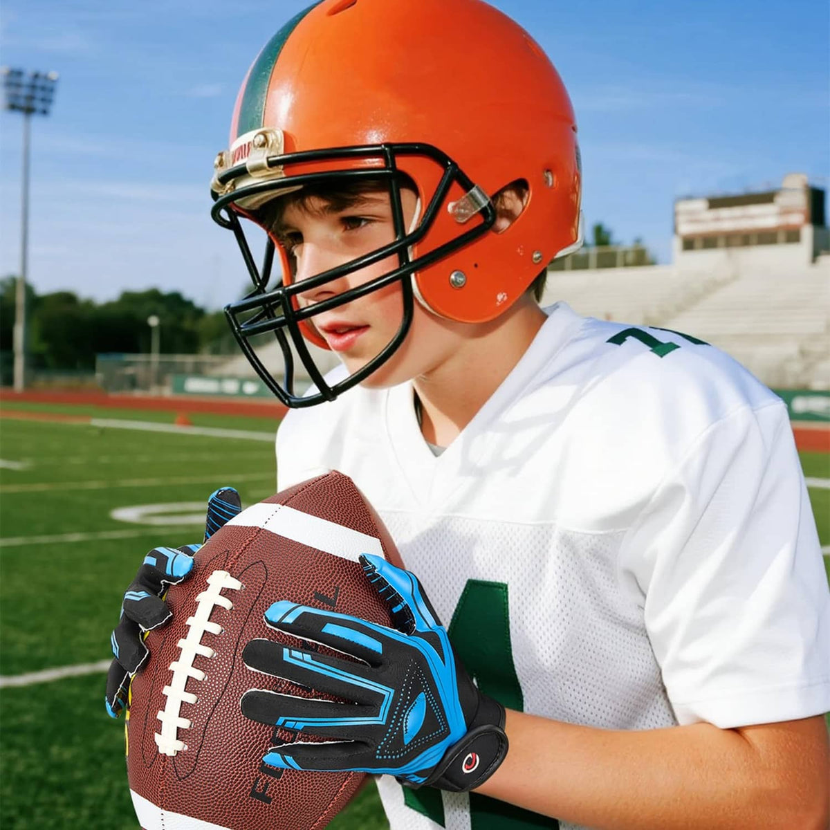 Youth receiver gloves in black with blue details on a football, close hand view
