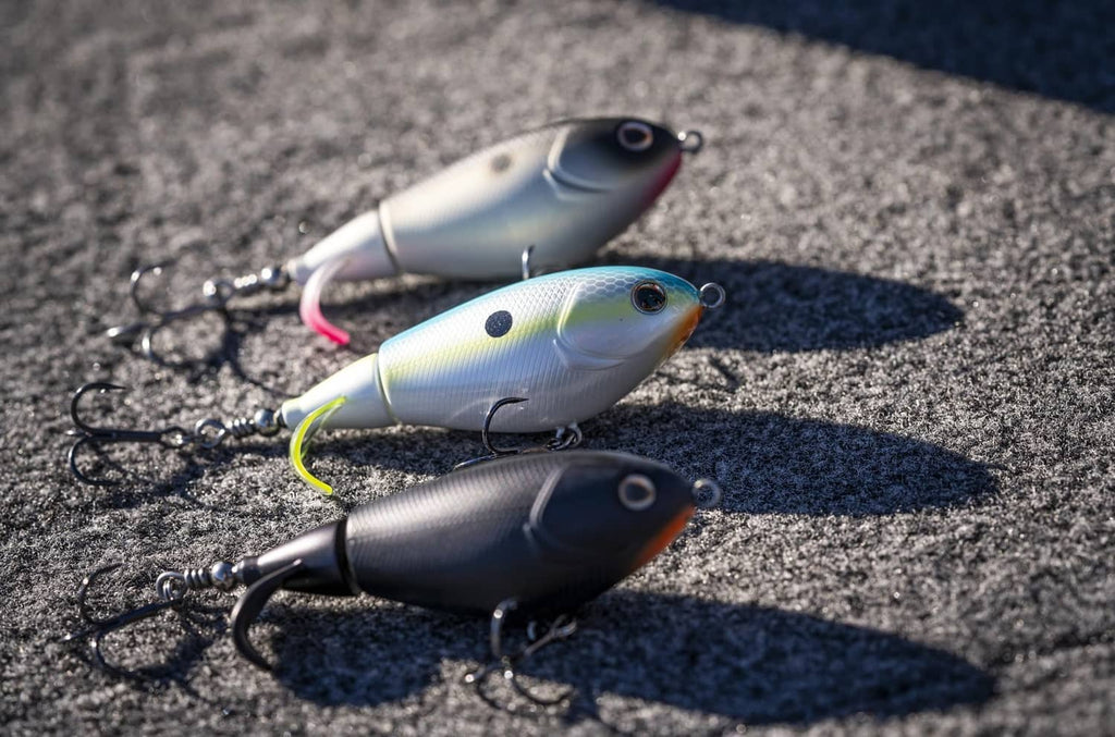 Set of three Berkley Choppo lures on pavement, metallic silver and dark bodies