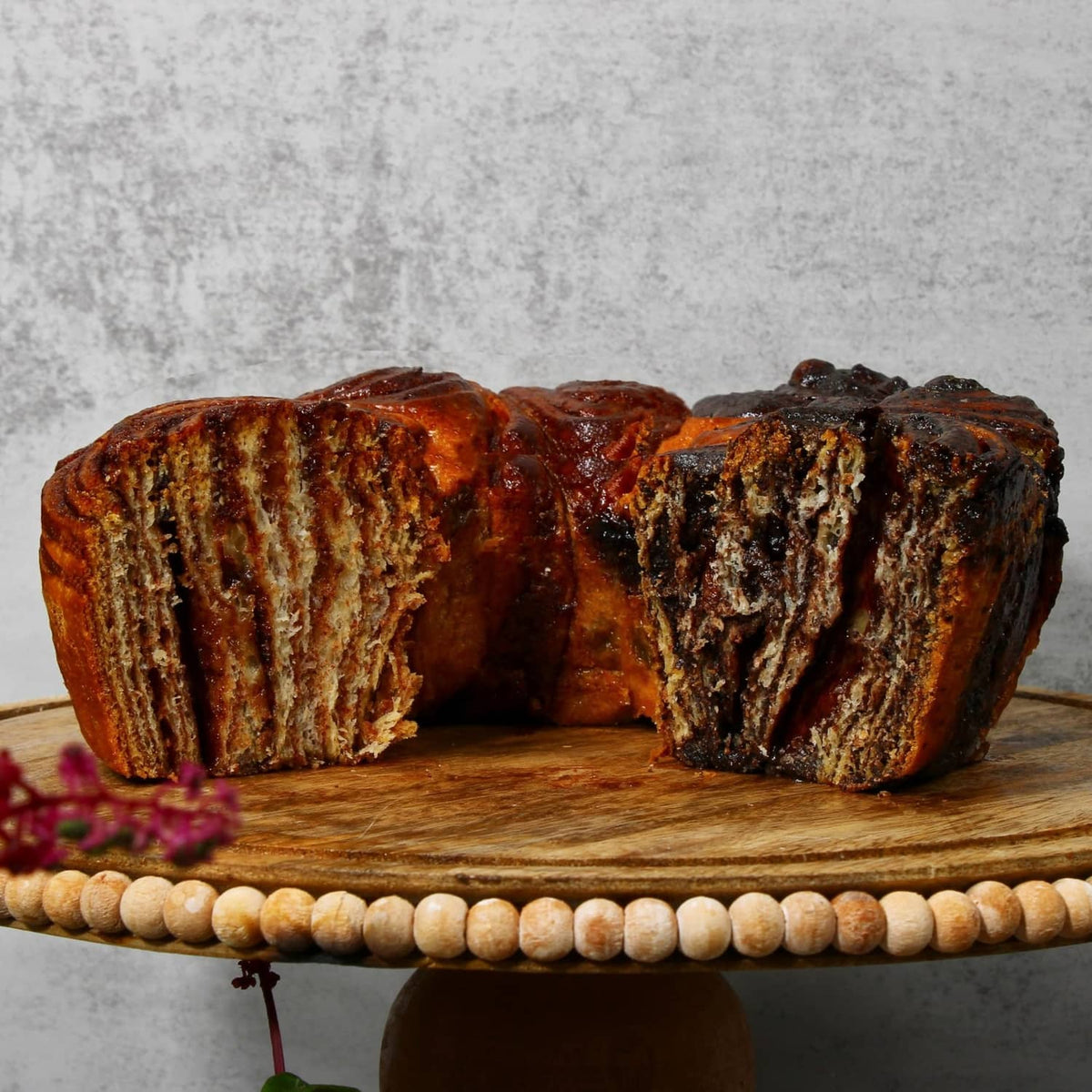 Chocolate and cinnamon babka cake cut halves on a round wooden board