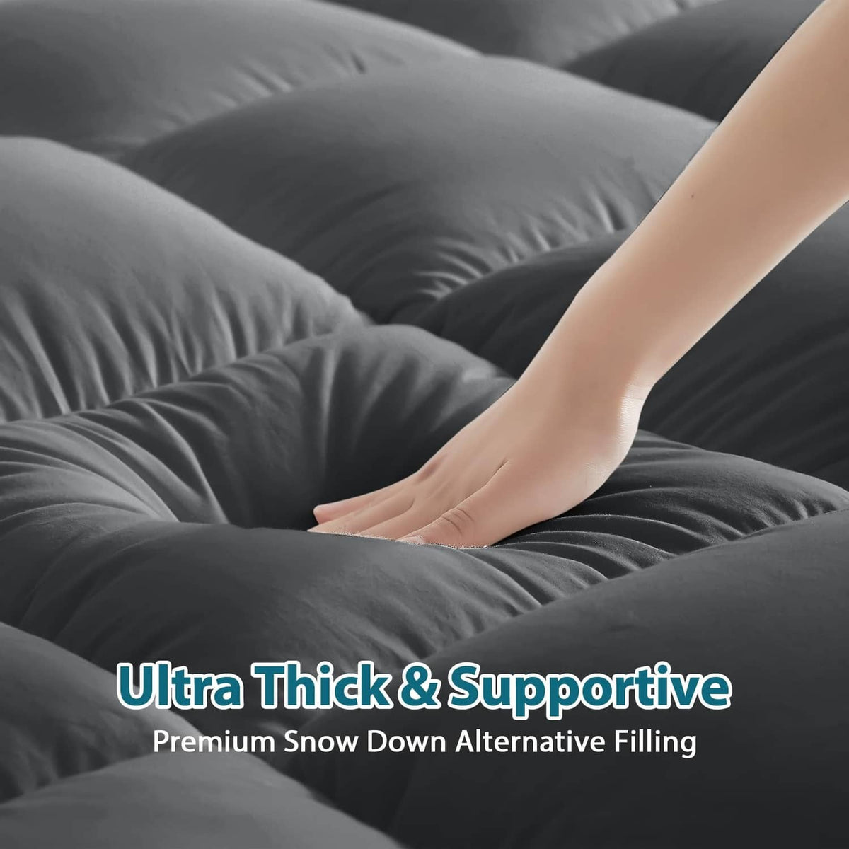 Grey quilted mattress topper with plush surface under hand pressure