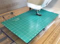 Green quilting frame mat with white grid markings for free-motion quilting