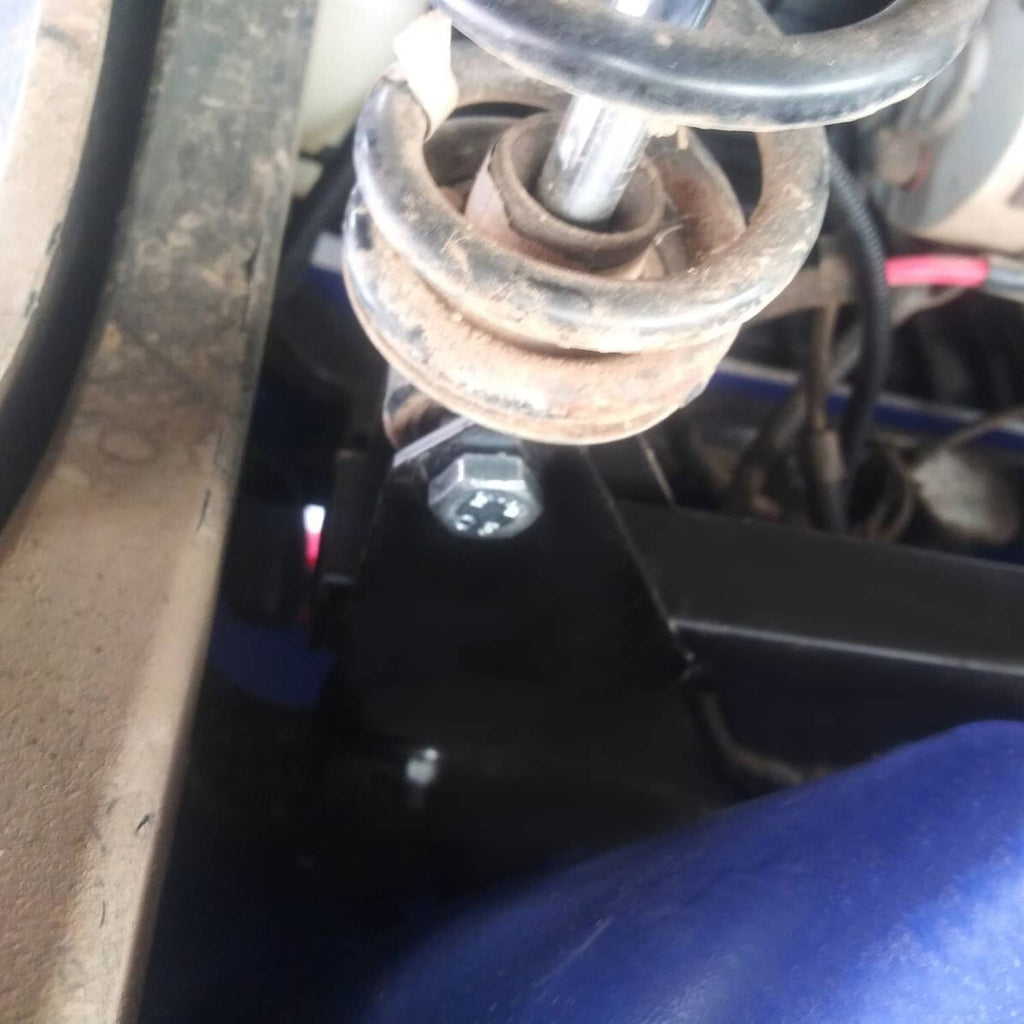 Black lift bracket and arm assembly installed undercart near wheel and steering area