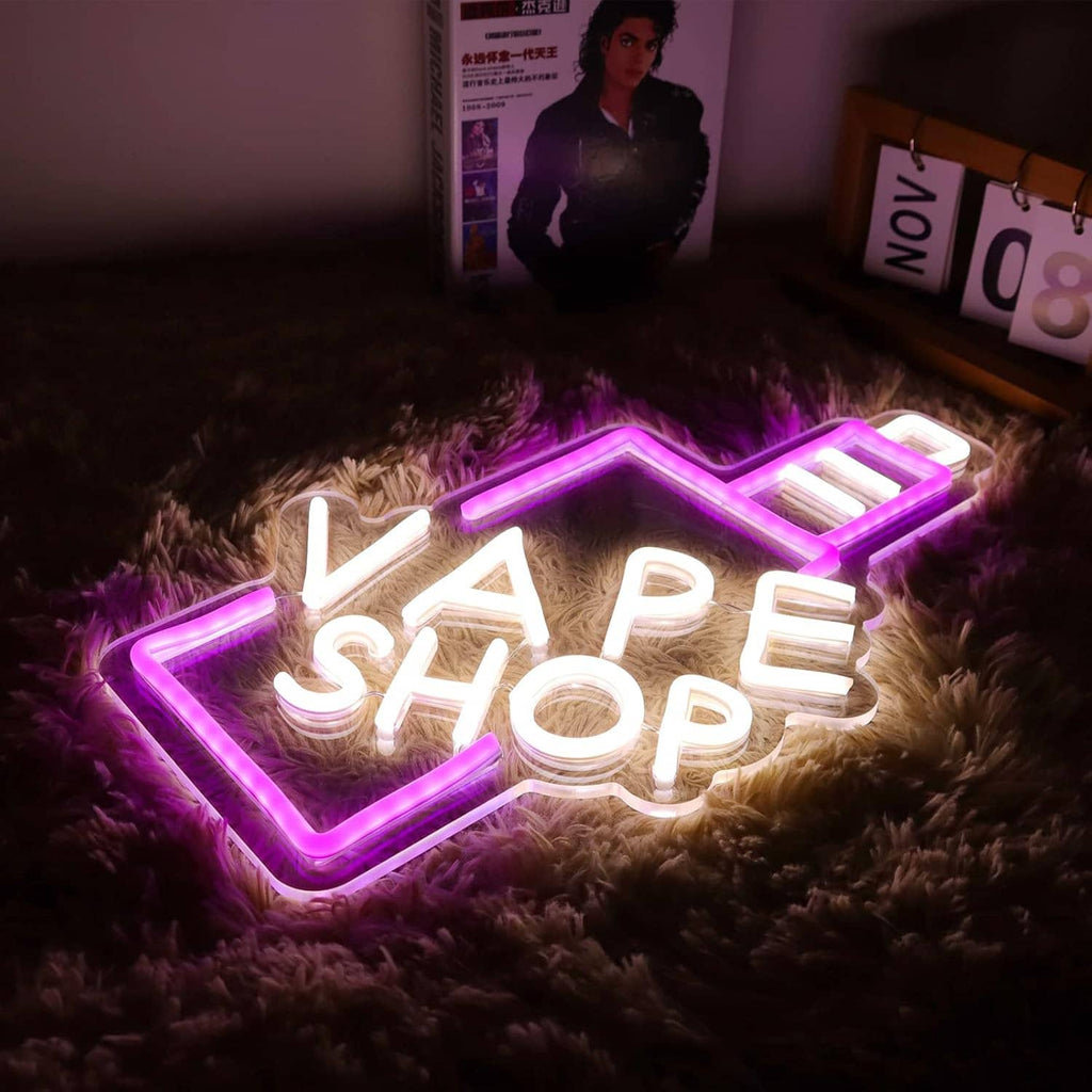 VAPE SHOP neon sign with pink outline arrow and white letters on a plush surface