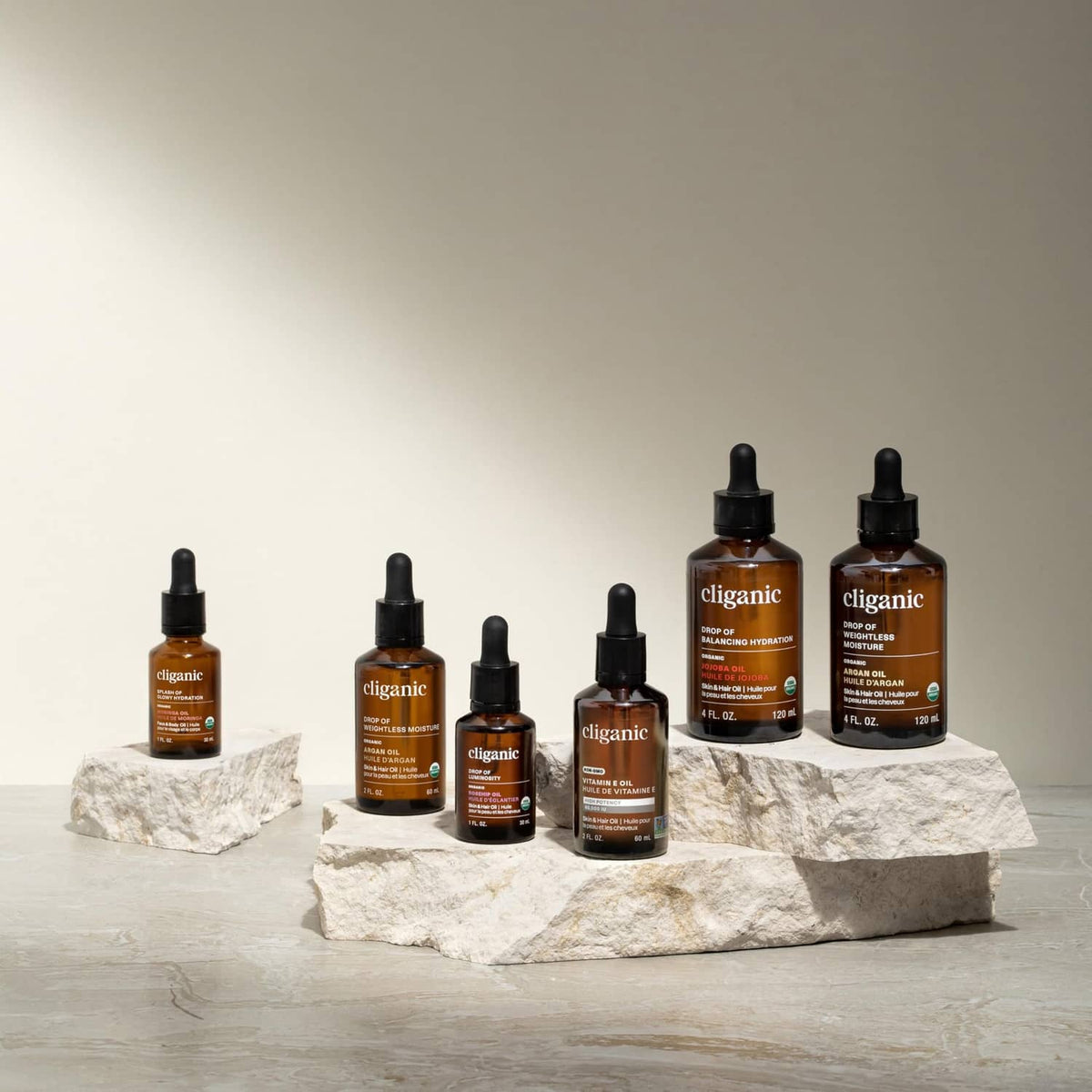 Cliganic argan oil bottles in different sizes lined up on paper