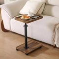 Adjustable side table with round wood tray and dark metal legs beside sofa