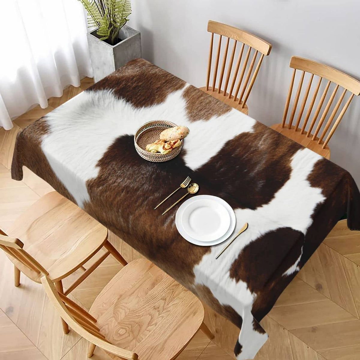 Cow print tablecloth with brown-and-white patches covering rectangular dining table