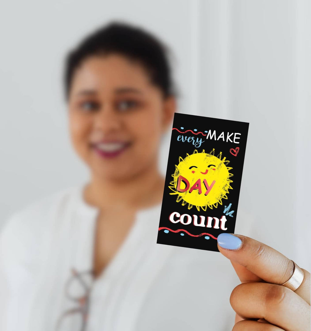 Hand holding a mini motivational card reading 'every day count' with a yellow sun
