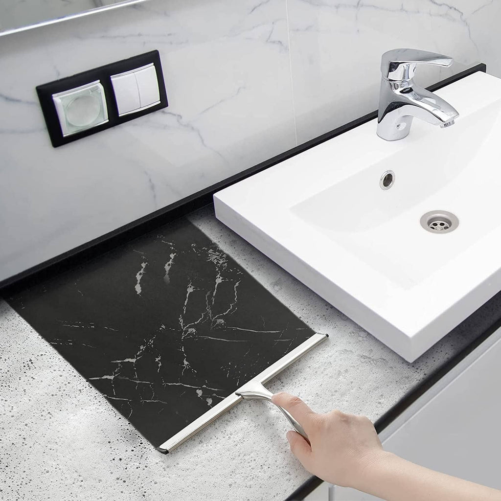 Bathroom squeegee with silver handle and black rubber blade lying near sink