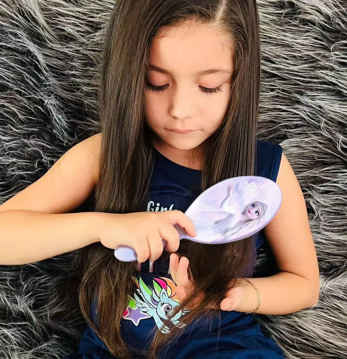Child holding a purple oval hairbrush with princess face on the handle