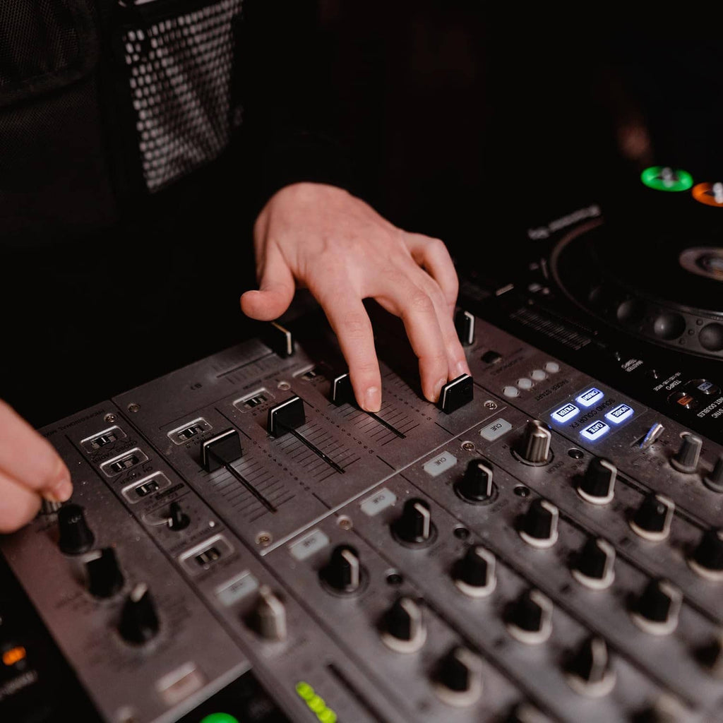 Hand installing a black fader cap onto a DJ mixer slider